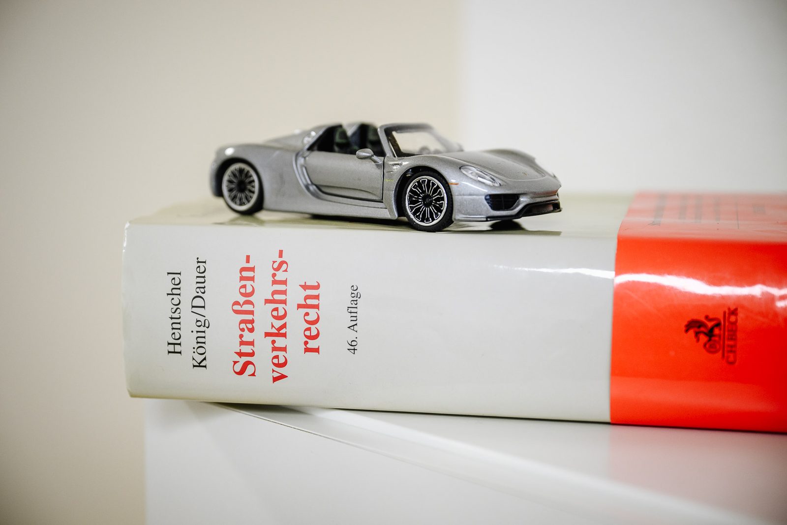 Modell eines Sportwagens auf dem Standardkommentar zum Straßenverkehrsrecht – Symbol für die Spezialisierung der Dr. Hofmann Rechtsanwalts GmbH auf Verkehrsrecht